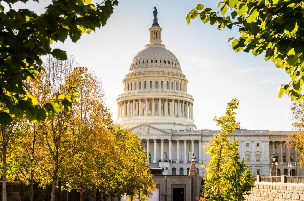 View of the Capitol Building in Washington DC Warmly Lit by an Afternoon Autumnal Sun. Some Colorful Trees are in Foreground.