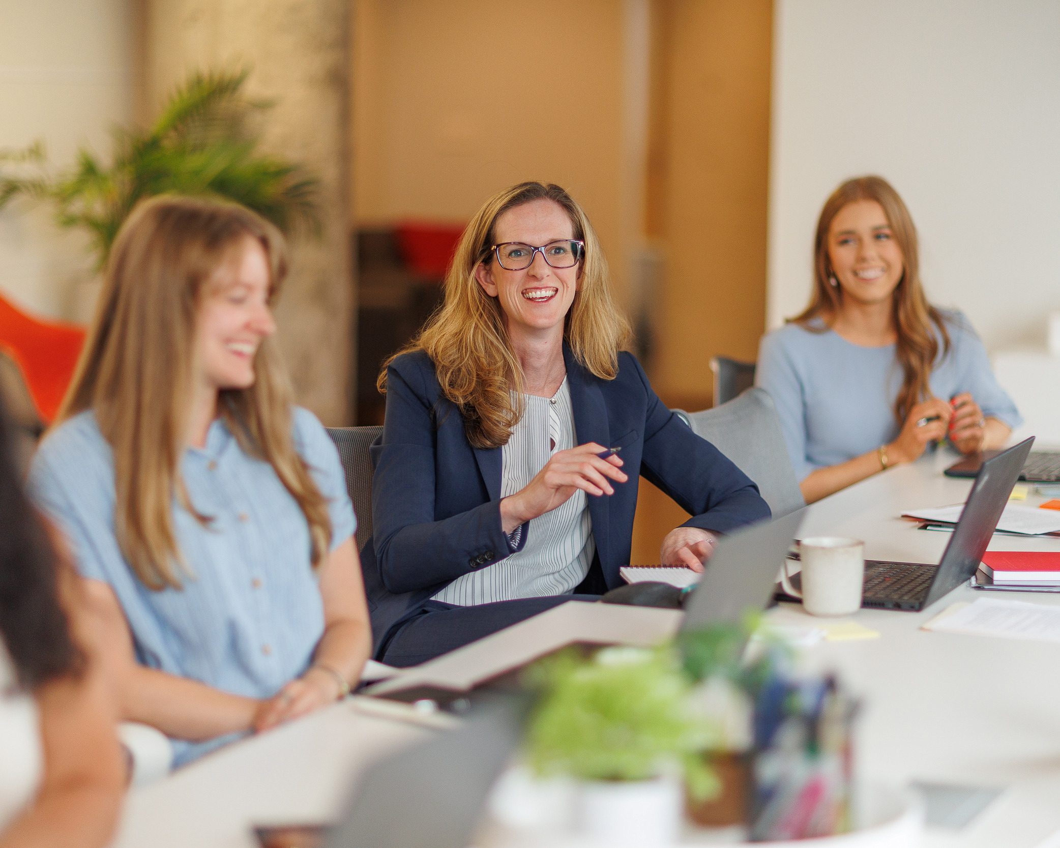 A group of women collaborating at a table, each using a laptop for work or discussion.
