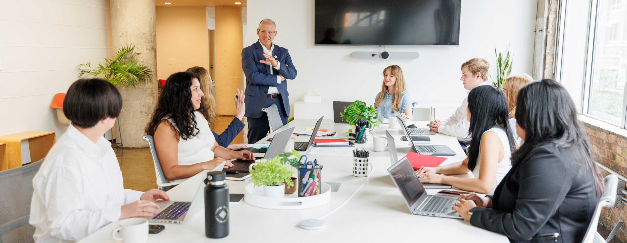 Team members working at a table in an office environment, smiling and collaborating.