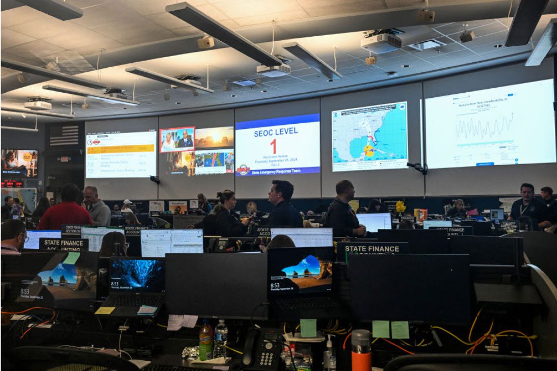 A large emergency operations center filled with people working on computers, focused on disaster preparedness, response, and crisis management.